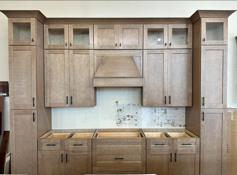 Greige stained kitchen wall with glass-front uppers, custom wood hood and pantry towers by Rodriguez Cabinets in Houston