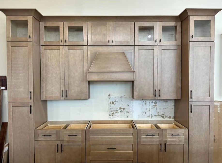 Greige maple kitchen wall with wood hood, glass transom cabinets and twin pantry towers built by Rodriguez Cabinets in Houston