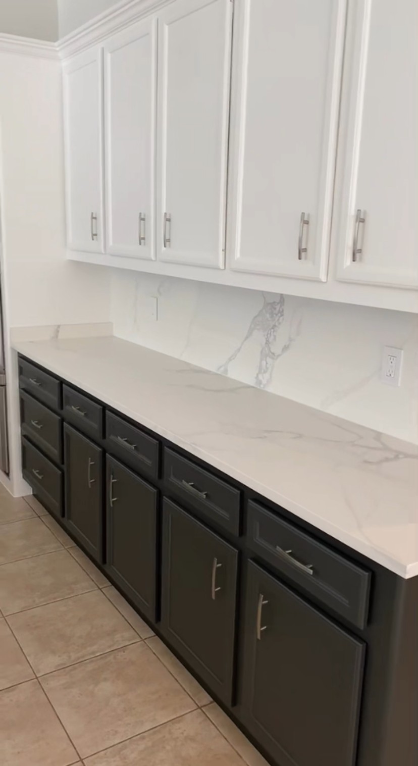 Two-tone kitchen with white uppers, charcoal base cabinets and quartz backsplash by Rodriguez Cabinets in Houston