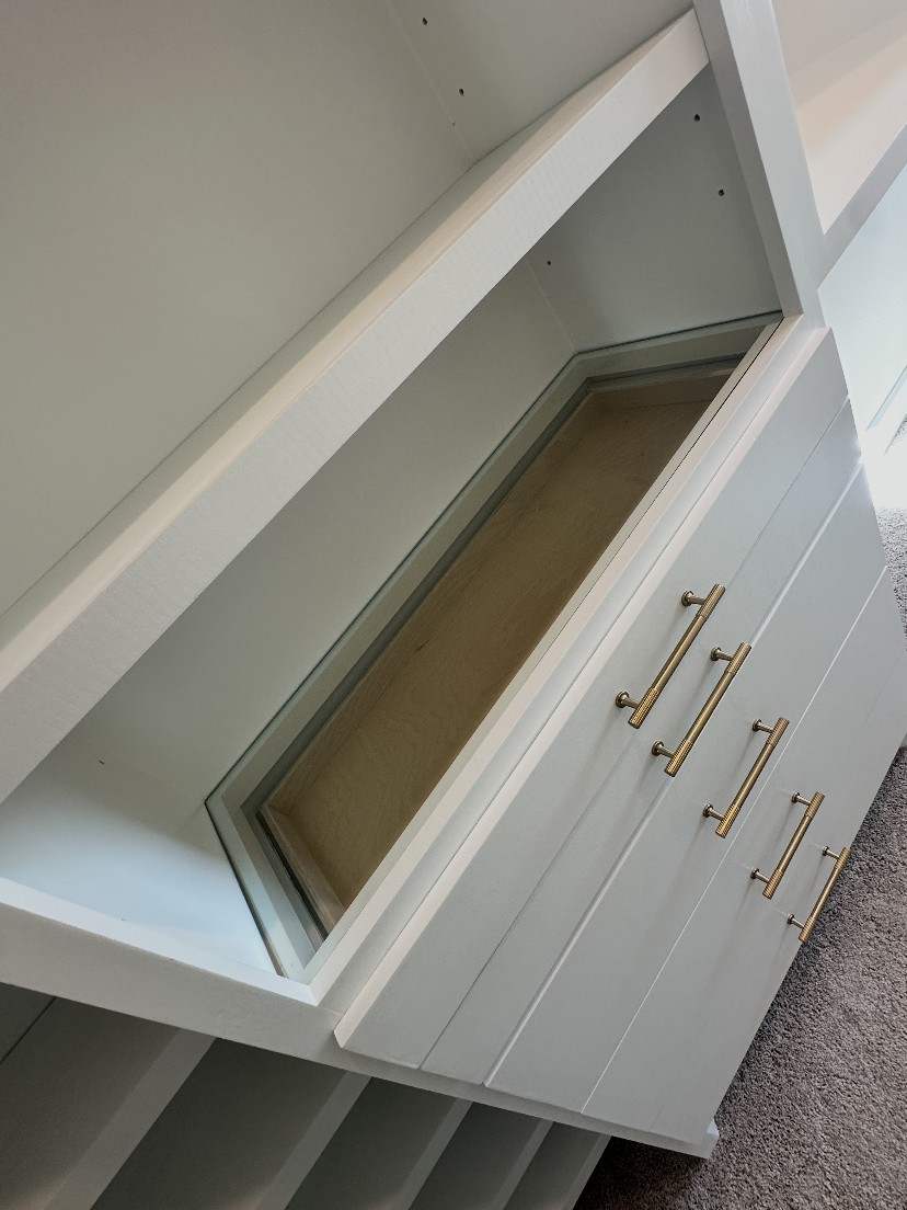 Closet dresser bank with glass-top display drawer and brass pulls by Rodriguez Cabinets in Houston