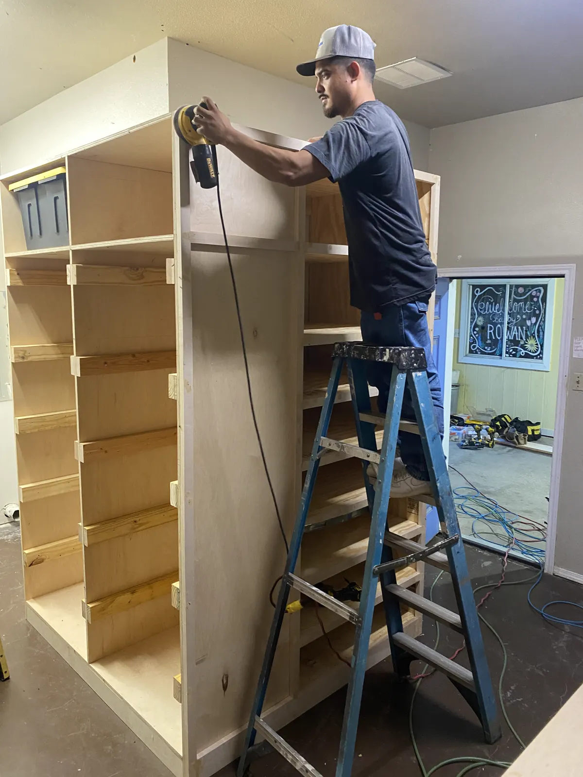 Craftsman sanding a cabinet carcass with an orbital sander